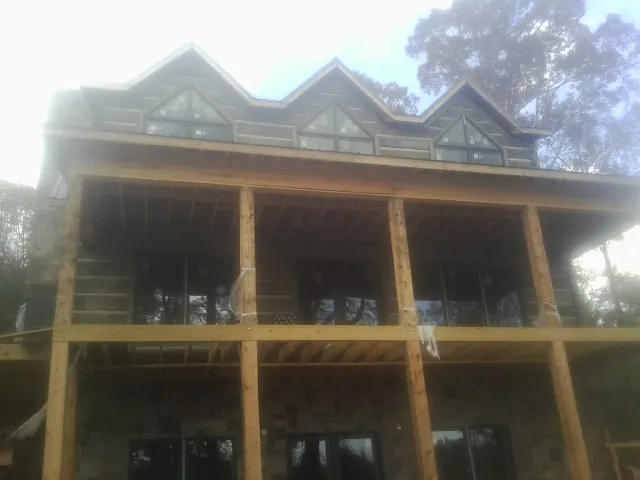 Dormers and porch framing on a large log home under construction — Roof Coating work by our crew in Gifford